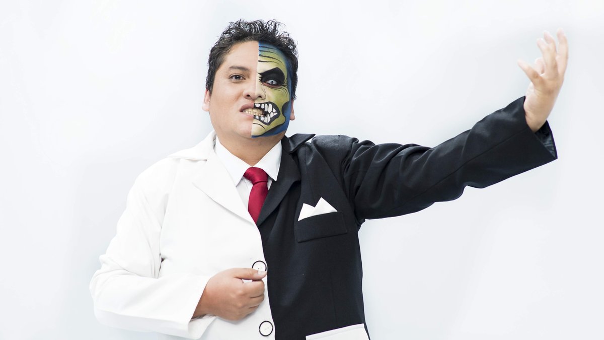 Wilson interpreta un personaje con traje y rostro divididos en dos mitades, con un brazo extendido.